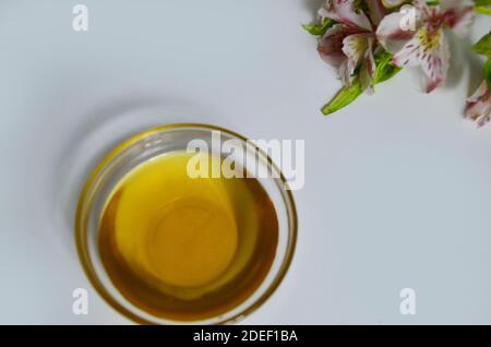 Image de sucre liquide pour les cheveux enlever la cire d'épilation pot de verre de miel doré fermer avec des fleurs frangipani. Préparation du traitement naturel du corps de beauté Banque D'Images