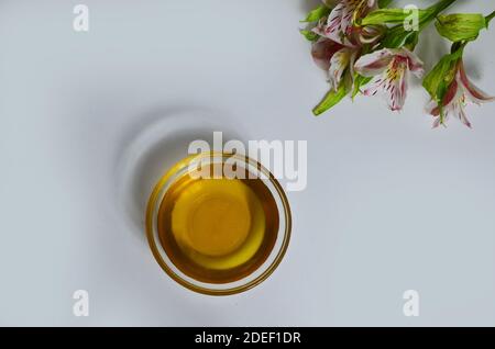 Image de sucre liquide pour les cheveux enlever la cire d'épilation pot de verre de miel doré fermer avec des fleurs frangipani. Préparation du traitement naturel du corps de beauté Banque D'Images