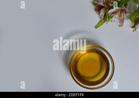 Image de sucre liquide pour les cheveux enlever la cire d'épilation pot de verre de miel doré fermer avec des fleurs frangipani. Préparation du traitement naturel du corps de beauté Banque D'Images