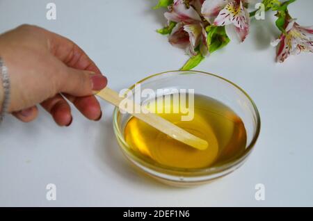 Image de sucre liquide pour les cheveux enlever la cire d'épilation pot de verre de miel doré fermer avec des fleurs frangipani. Préparation du traitement naturel du corps de beauté Banque D'Images