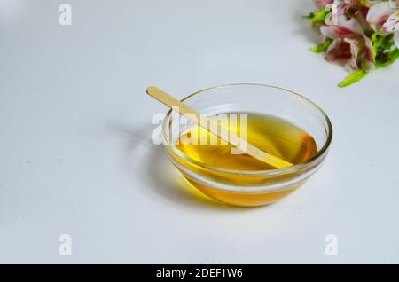 Image de sucre liquide pour les cheveux enlever la cire d'épilation pot de verre de miel doré fermer avec des fleurs frangipani. Préparation du traitement naturel du corps de beauté Banque D'Images