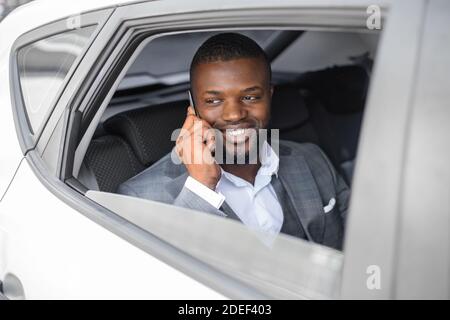 Homme d'affaires noir souriant ayant une conversation téléphonique Banque D'Images