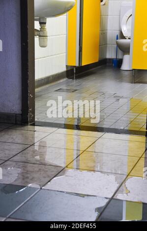 Flaques d'eau sur le sol carrelé d'une salle de bains/toilettes publiques de l'aéroport. Inondation. Inondations dues à la tempête. Banque D'Images