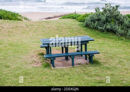 Table de pique-nique verte sur une pente herbeuse surplombant la mer Banque D'Images