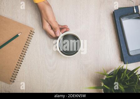 Femme main tenant une tasse de café noir chaud environ pour boire pour se rafraîchir tout en travaillant au bureau Banque D'Images