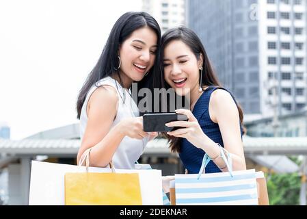 De belles amies asiatiques aiment faire des achats en ligne par téléphone mobile lors de votre voyage en ville Banque D'Images