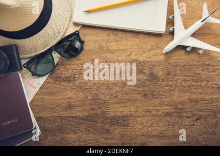 Gadgets de voyage comprenant un appareil photo, une carte, un carnet, un passeport, des lunettes de soleil et un modèle d'avion sur fond de table en bois, vue du dessus de la bordure avec copie Banque D'Images