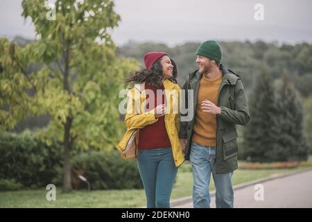 Jeune couple qui marche dans le parc et qui a l'air heureux Banque D'Images