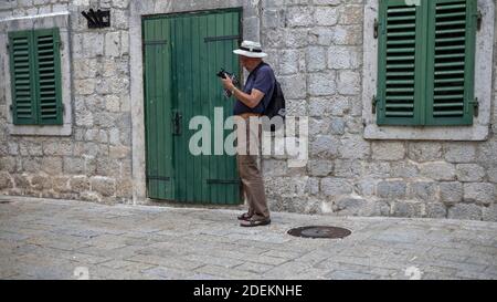 Monténégro, 22 septembre 2019 : un photographe qui ajuste son appareil photo dans la rue de la vieille ville de Kotor Banque D'Images