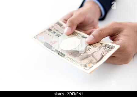 Mains d'un homme donnant des milliers de yens japonais d'argent sous forme de billets sur table blanche Banque D'Images