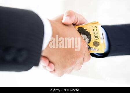 Les hommes d'affaires faisant poignée de main avec de l'argent, la Corée du Sud a gagné des billets, en mains - corruption concept Banque D'Images