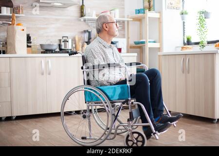 Homme âgé handicapé en fauteuil roulant se sentant seul et regardant la fenêtre. Pensionné handicapé âgé après une blessure et une réadaptation, paralysie et invalidité pour invalide déprimé plein de tristesse, de souci et de visage triste. Période de retraite pour les personnes âgées Banque D'Images