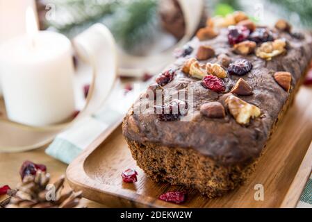 Délicieux délicieux gâteau aux fruits secs aux fruits à coque et aux baies maison sur une table en bois avec des articles de décoration pour célébrer la saison des fêtes Banque D'Images