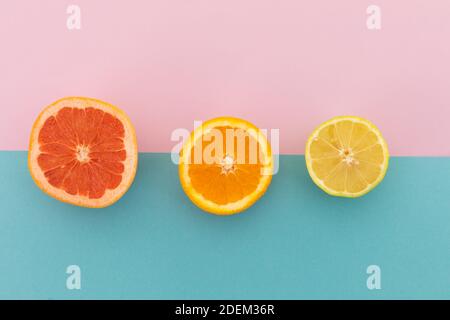 Pamplemousse, orange et citron sur fond rose et bleu Banque D'Images