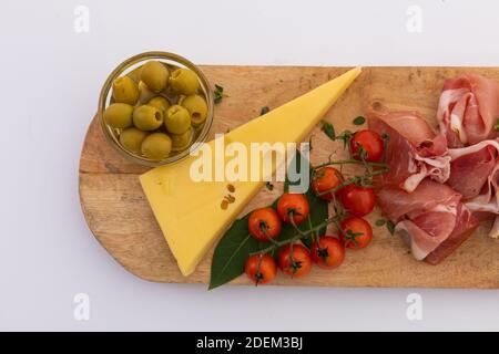 Olives, fromage, jambon et tomates cerises sur bois sur fond blanc Banque D'Images