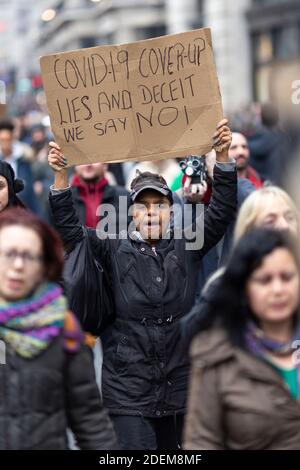 Manifestation anti-verrouillage, Londres, 28 novembre 2020. Une femme noire marchant et tenant un écriteau de protestation au-dessus de sa tête. Banque D'Images