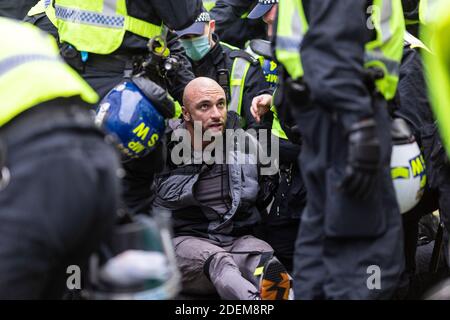 Manifestation anti-verrouillage, Londres, 28 novembre 2020. Un manifestant arrêté se trouve dans la rue entourée de policiers. Banque D'Images