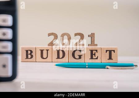 Concept du budget de 2021. 2021 cubes en bois budget, calculatrice et stylo sur table de bureau en bois. Banque D'Images