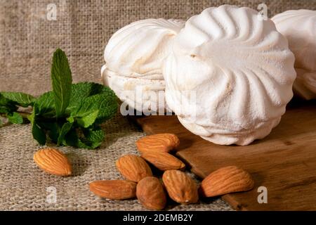 zephyr blanc, amandes pelées et un petit bouquet de menthe fraîche couché sur un sac de toile et de bois vieilli Banque D'Images