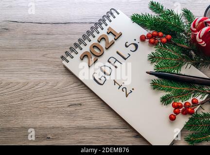 Objectifs et concept de résolution des nouvelles années. Liste des objectifs du nouvel an 2021. Stylo, carnet et décorations de noël isolés sur fond de bois Banque D'Images