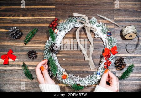 Cadre en couronne de pin et de Noël et mains de femmes sur un fond en bois. Pose à plat, style élégant. Noël, nouvel an, préparation pour le Banque D'Images