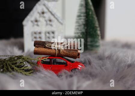 NIS, Serbie - 29 novembre 2020 voiture de jouet avec une pile de souches sur le toit sur un tapis de fourrure comme la neige devant une petite maison blanche Banque D'Images