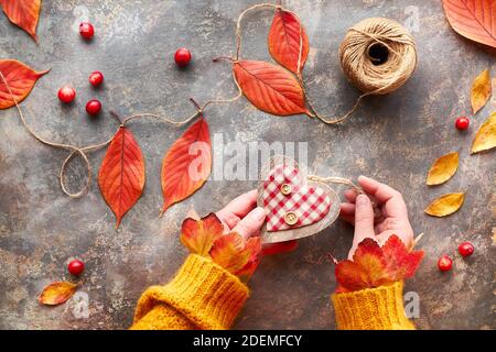 Décorations d'automne à fabriquer soi-même en matériaux naturels. Fabrication de guirlande florale avec cordon et feuilles d'automne Banque D'Images