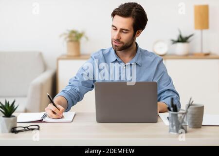 Entrepreneur confiant prenant des notes travailler assis au bureau Banque D'Images