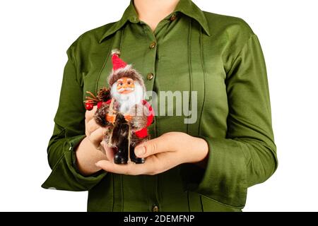 Photo isolée d'une jeune fille en chemise verte tenant un jouet de figurine de père noël sur fond blanc. Banque D'Images