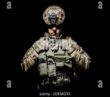 Photo d'un soldat ombré entièrement équipé dans un gilet d'armure et un casque debout sur fond noir. Banque D'Images