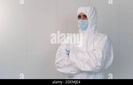 Un professionnel de la santé en costume de protection traverse ses bras à l'hôpital pendant la pandémie causée par le coronavirus Covid 19. L'infirmière masculine porte une surfeur Banque D'Images