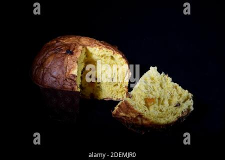 Panettone italien artisanal doux et doux avec une coupe en tranches sur fond noir et lumière de coupe Banque D'Images