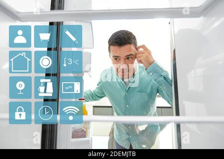 L'homme à la recherche de nourriture dans un réfrigérateur vide cuisine à Banque D'Images