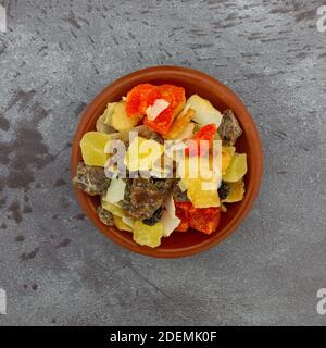 Vue de dessus d'un petit bol rempli de plusieurs variétés de fruits secs sur une table marbrée. Banque D'Images