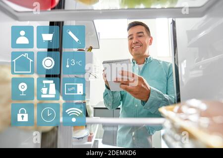 Man making liste des aliments nécessaires à la maison d''un réfrigérateur Banque D'Images