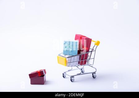 Chariot miniature avec cadeaux sur fond blanc. Concept commercial vacances. Gros plan. Banque D'Images