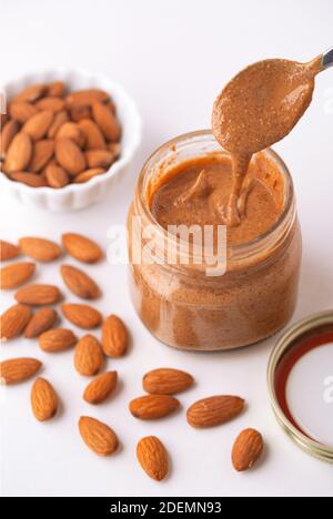 Petit pot de beurre d'amande biologique frais avec une cuillère goutte dans le bol Banque D'Images