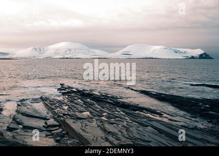 Collines éloignées sous la neige et rivage en premier plan en hiver Scène sur les îles Orcades Banque D'Images