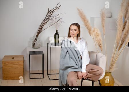 Chemise blanche élégante brune jeune, style décontracté, look moderne, portrait élégant et minimaliste à l'intérieur, fleurs séchées décoratives. Banque D'Images