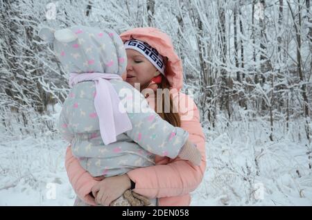 Famille marchant dans les bois d'hiver petite fille et sa mère marchent dans la forêt d'hiver. Jouer avec la neige et le traîneau. Dans les vêtements chauds d'hiver Banque D'Images