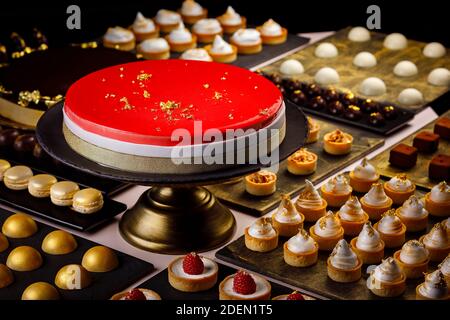 Grand gâteau aux baies servi avec une sélection de quiches, tartes, macarons et bouche d'amuse-bouche au chocolat Banque D'Images