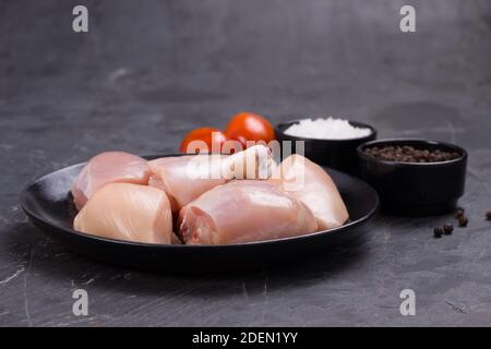 Poulet cru tendre curry coupé sans peau disposé sur noir assiette avec ingrédients de cuisson sur fond blanc Banque D'Images