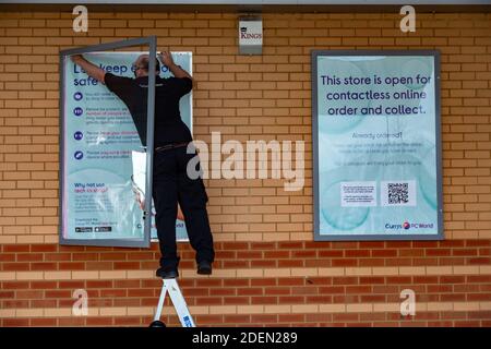 Kidderminster, Worcestershire, Royaume-Uni. 1er décembre 2020. Un membre du personnel de Currys PC World à Kidderminster remplace les affiches à l'extérieur du magasin dans le parc commercial de la ville avant la réouverture le 2 décembre. La ville passe au niveau 2, ce qui permet à des magasins non essentiels de rouvrir. Crédit : Peter Lophan/Alay Live News Banque D'Images