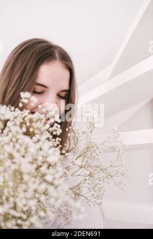 Portrait de jeune belle femme par la fenêtre avec l'ombre des fleurs sur son visage. Esthétique du printemps du matin Banque D'Images