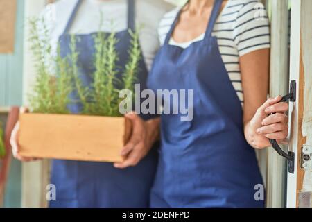 Homme aux herbes de romarin et femme tenant la poignée de porte Banque D'Images