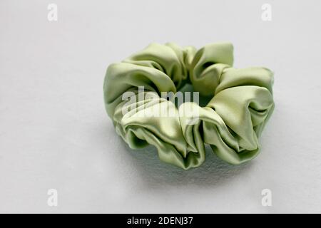 Soie verte Scrunchy isolé sur fond blanc. Outil de coiffure Flat Lay de l'élastique coloré de cheveux de bande, Bobble Scrunchie bandeau Banque D'Images