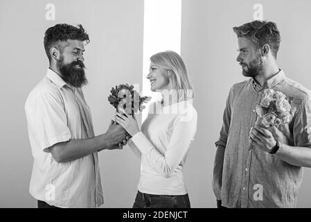 Hommes concurrents avec bouquets fleurs essayer de conquérir fille. Une fille souriante a fait son choix. Concept cœur brisé. Femme heureuse prend bouquet fleurs cadeau romantique. Fille populaire recevoir beaucoup d'attention masculine. Banque D'Images