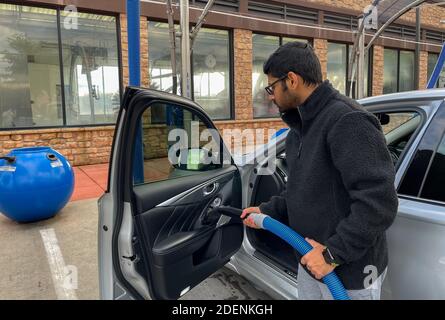 McKinney, TX / USA - 30 novembre 2020: Vue rapprochée d'un homme utilisant le tuyau d'aspiration pour aspirer sa voiture dans le stationnement sous vide libre-service Banque D'Images