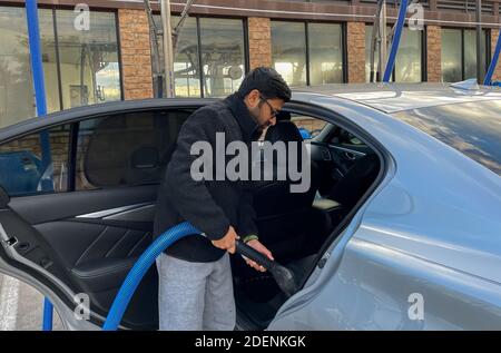 McKinney, TX / USA - 30 novembre 2020: Vue rapprochée d'un homme utilisant le tuyau d'aspiration pour aspirer sa voiture dans le stationnement sous vide libre-service Banque D'Images