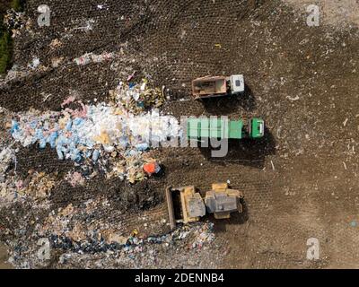 Vue de dessus de la décharge avec différents déchets. Tracteur jaune. Camion à ordures vert. Tri des déchets. Respect de l'environnement. Banque D'Images